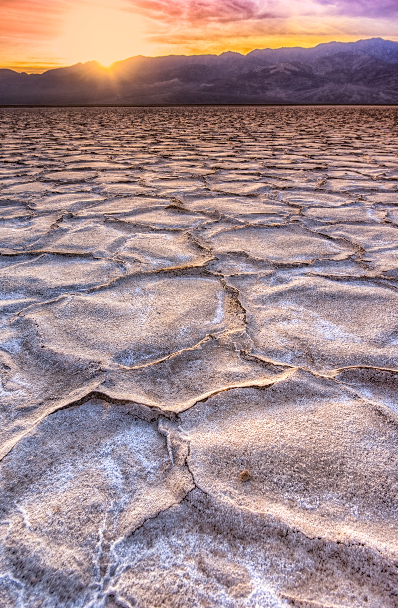 The low angle of the setting sun highlights the hexagonal plates of salt crystals in Badwater Basin in Death BValley National Park, California