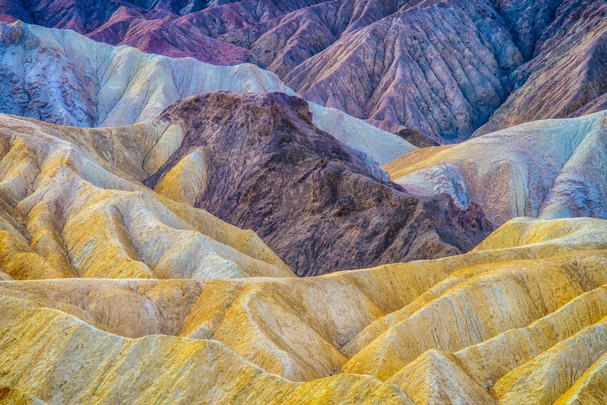 This is a close-up view of the margin between the yellow Furnace Creek Formation and the multi-colored Artist's Drive formation visible from Zabriskie Point Overlook, which is accessible from Highway 190 in Death Valley National Park.