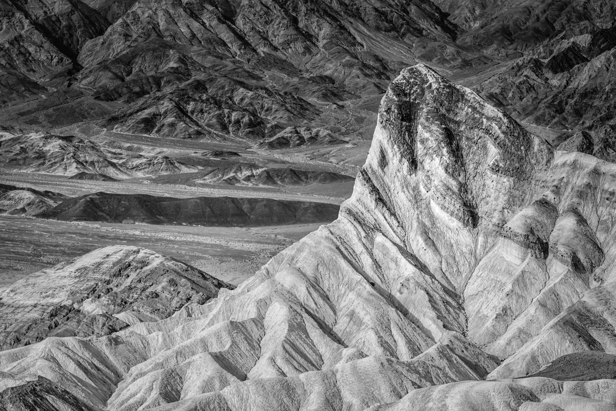 This black-and-white photograph features Manly Beacon. This viewpoint is accessible from the Zabriskie Point Overlook, which is accessible from Highway 190 in Death Valley National Park.