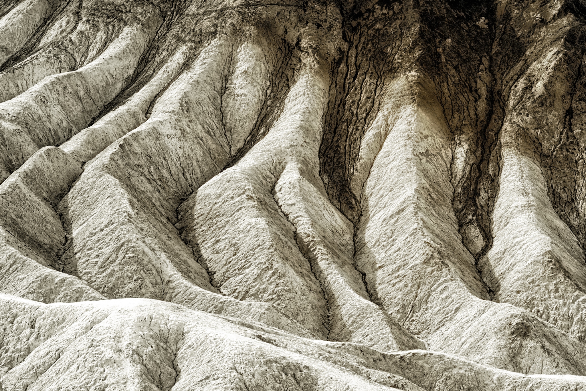 The badlands visible from the Zabriskie Point Overlook, which is accessible from Highway 190 in Death Valley National Park, are examples of dendritic drainage caused by periodic flooding.