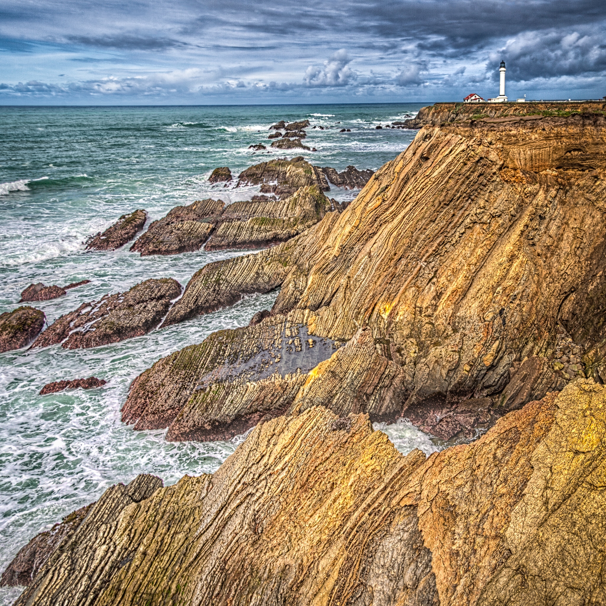 Tar sands occur interbedded with Monterey shale and shaly sandstone to create a dramatic foreground for the Point Arena Lighthouse near the Point Arena-Stornetta Unit, along California's northern coast, south of Mendocino.