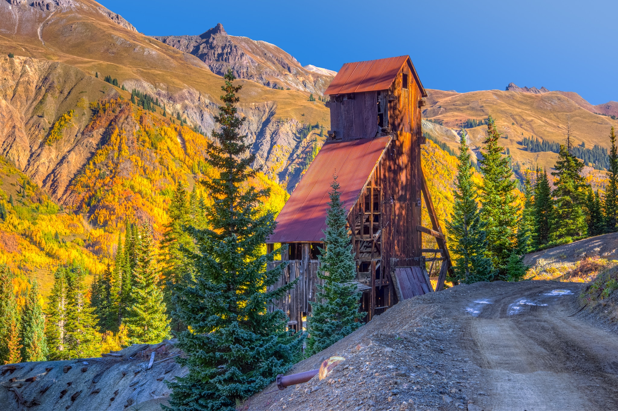 Morning light picks out features on the headframe of the Yankee Girl Mine near Ouray, CO, on Ouray County Road 31. In the distance aspens and scrub oal color the mountainside.