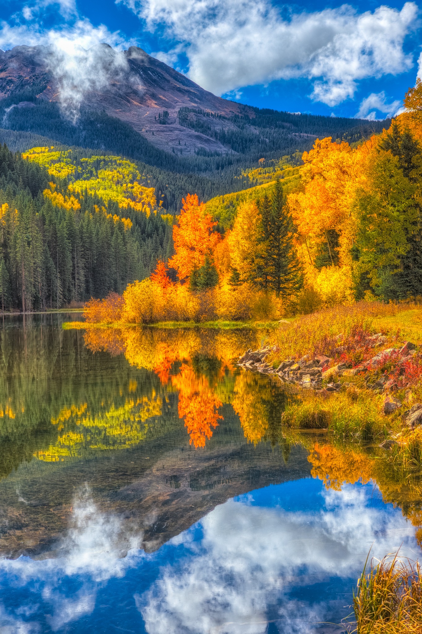 Colorful aspen trees are reflected on the surface of Woods Lake, at the end of Fall Creek Road, near Telluride, Colorado.
