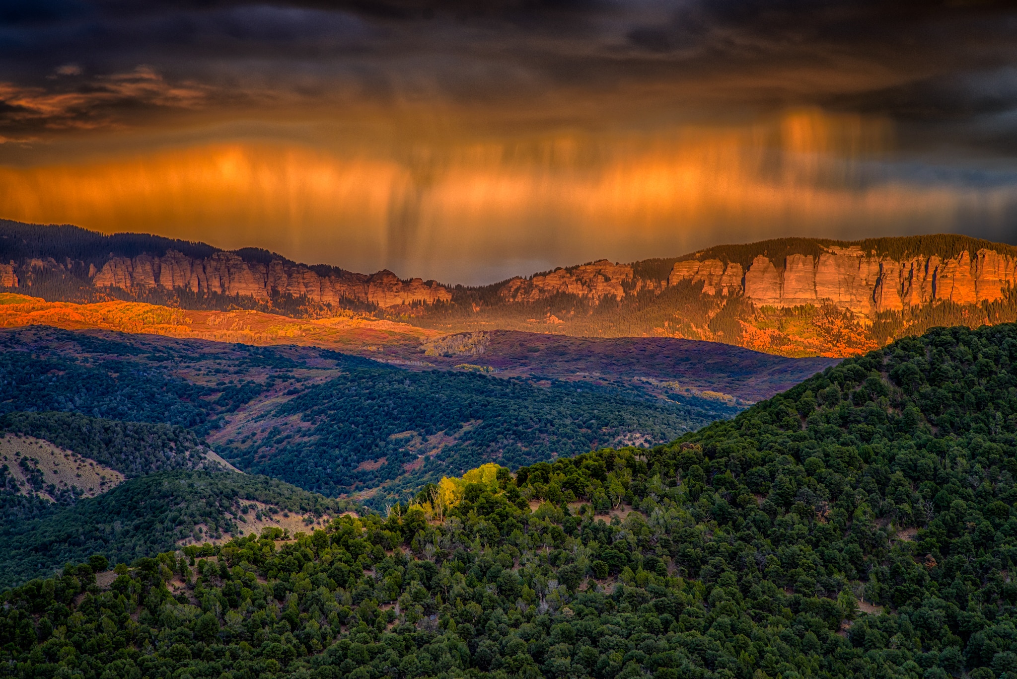 Virga over the Cimarron mountains catches the light of the setting sun, as seen from Ridgeway State Park, Colorado.