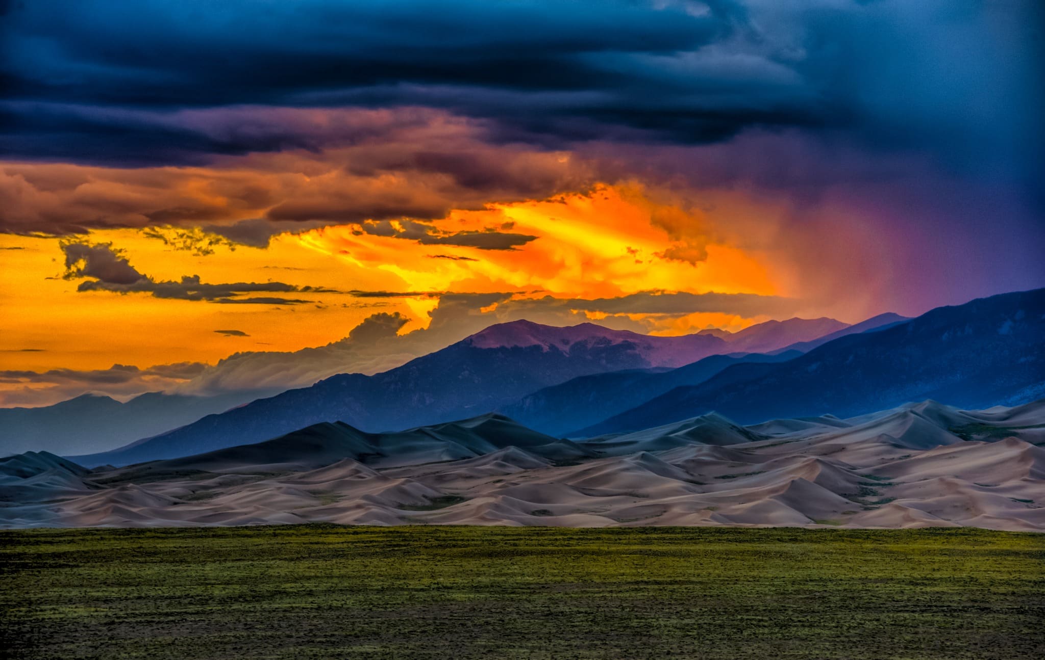 Sunsets are dramatic and colorful when competing with storm clouds at Great Sand Dunes National Park and Preserve near Alamosa, Colorado
