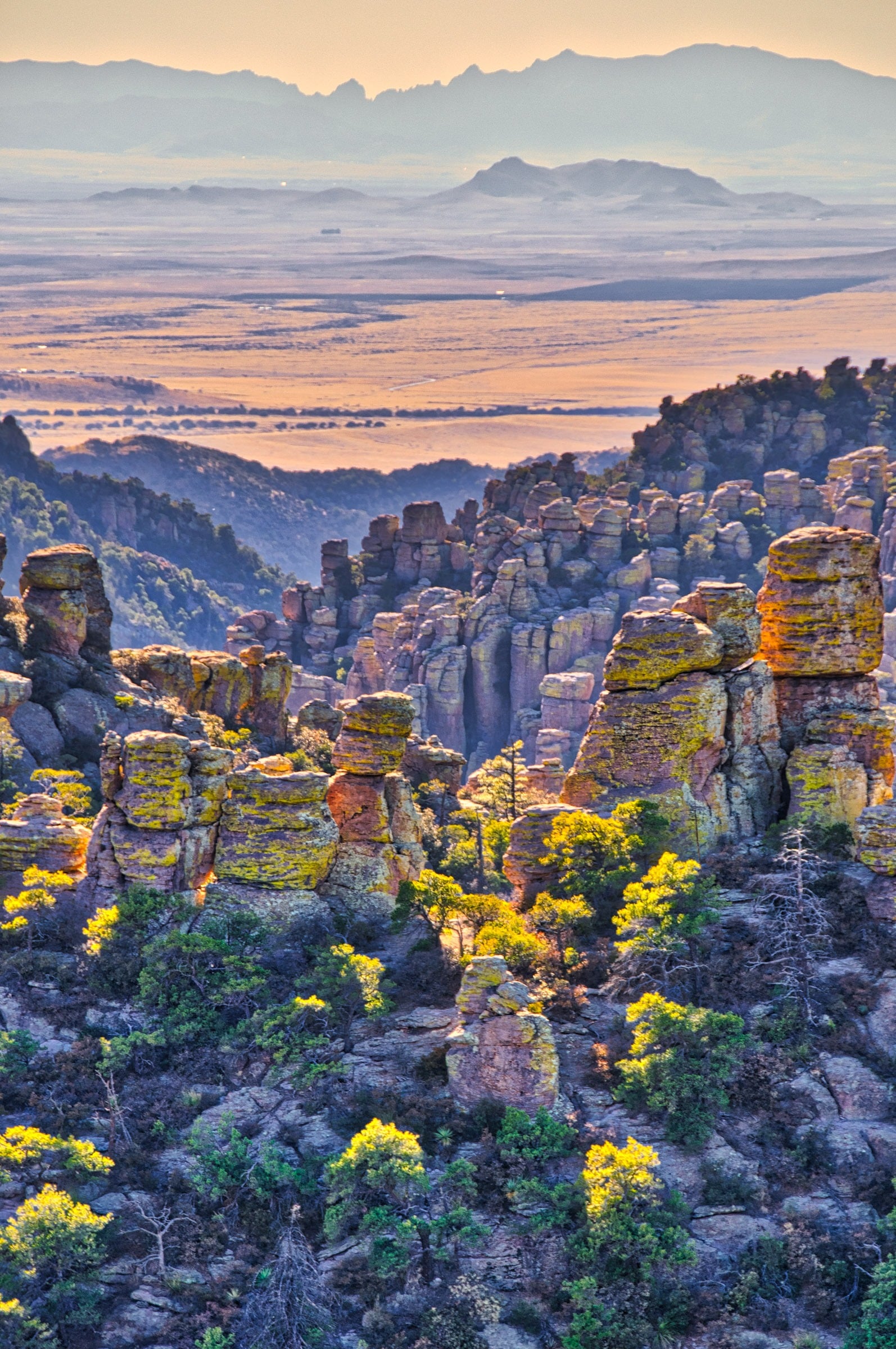 Sunset light illuminates the sides of rhyolite pinnacles, as well as the vallies beyon, in Chiricahua National Monument in Arizona.