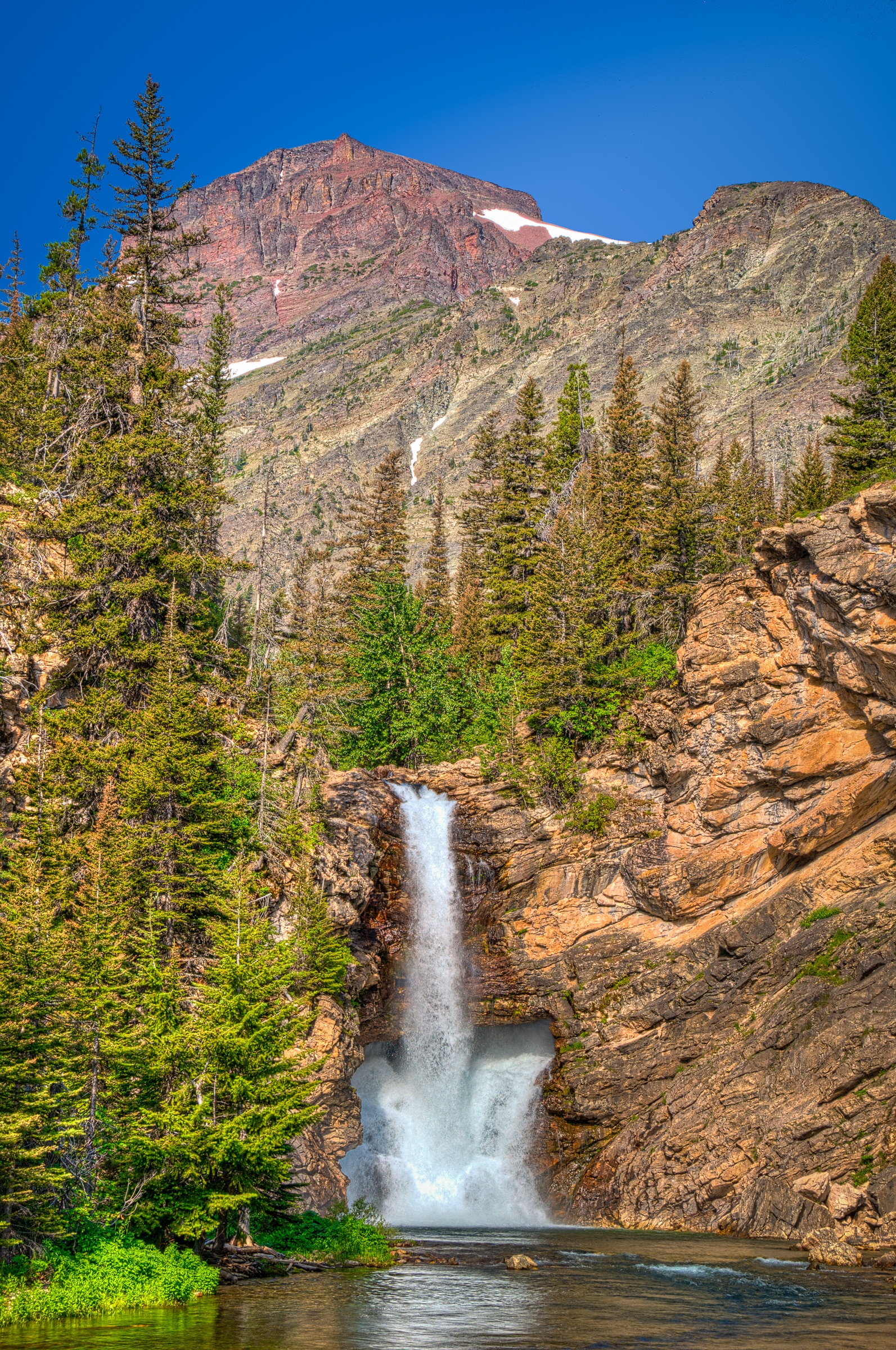 Running Eagle Falls, also known as Trick Falls, flows off the outlet stream between Two Medicine Lake and Lower Two Medicine Lake.