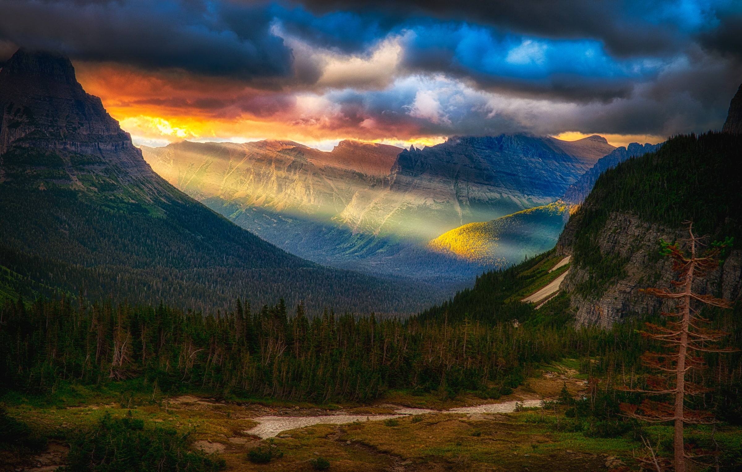 Crepuscular rays beam through the stormy dawn at Logan Pass on the Going-to-the-Sun Road in Glacier National Park, Montana.