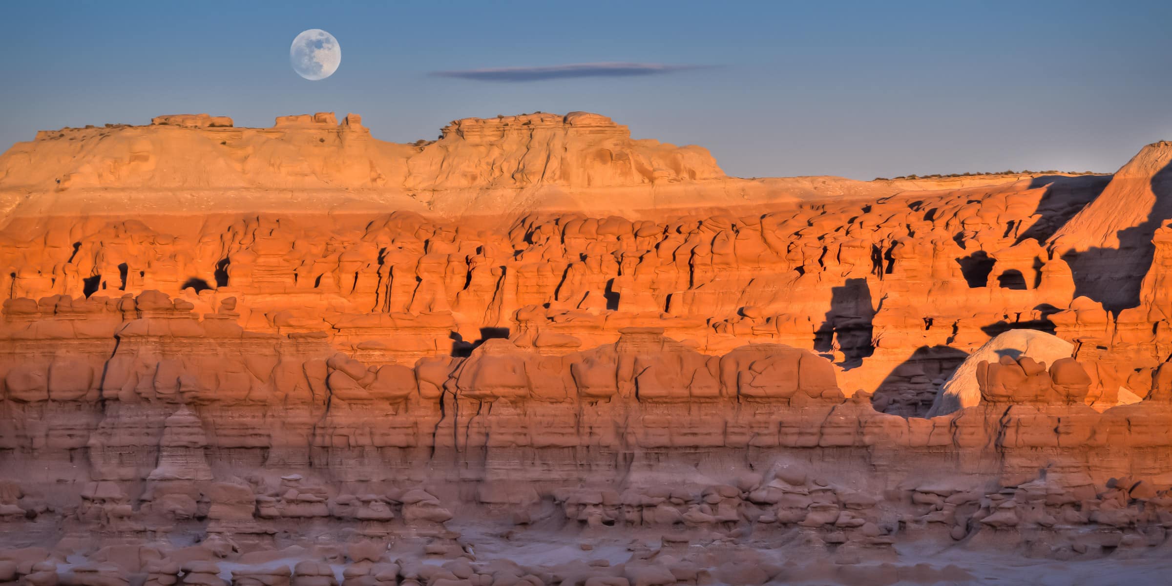 The full moon rises over Goblin Valley State Park at sunset.