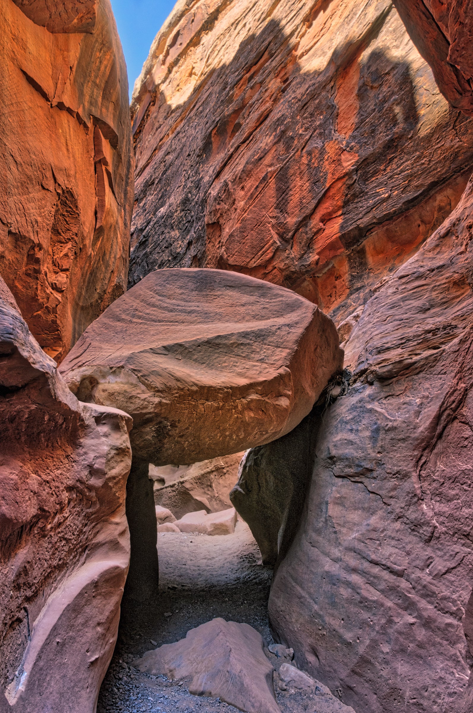 A boulder creates a tunnel through Bell Canyon, a slot canyon off Wild Horse Road near Goblin Valley State Park in Utah.