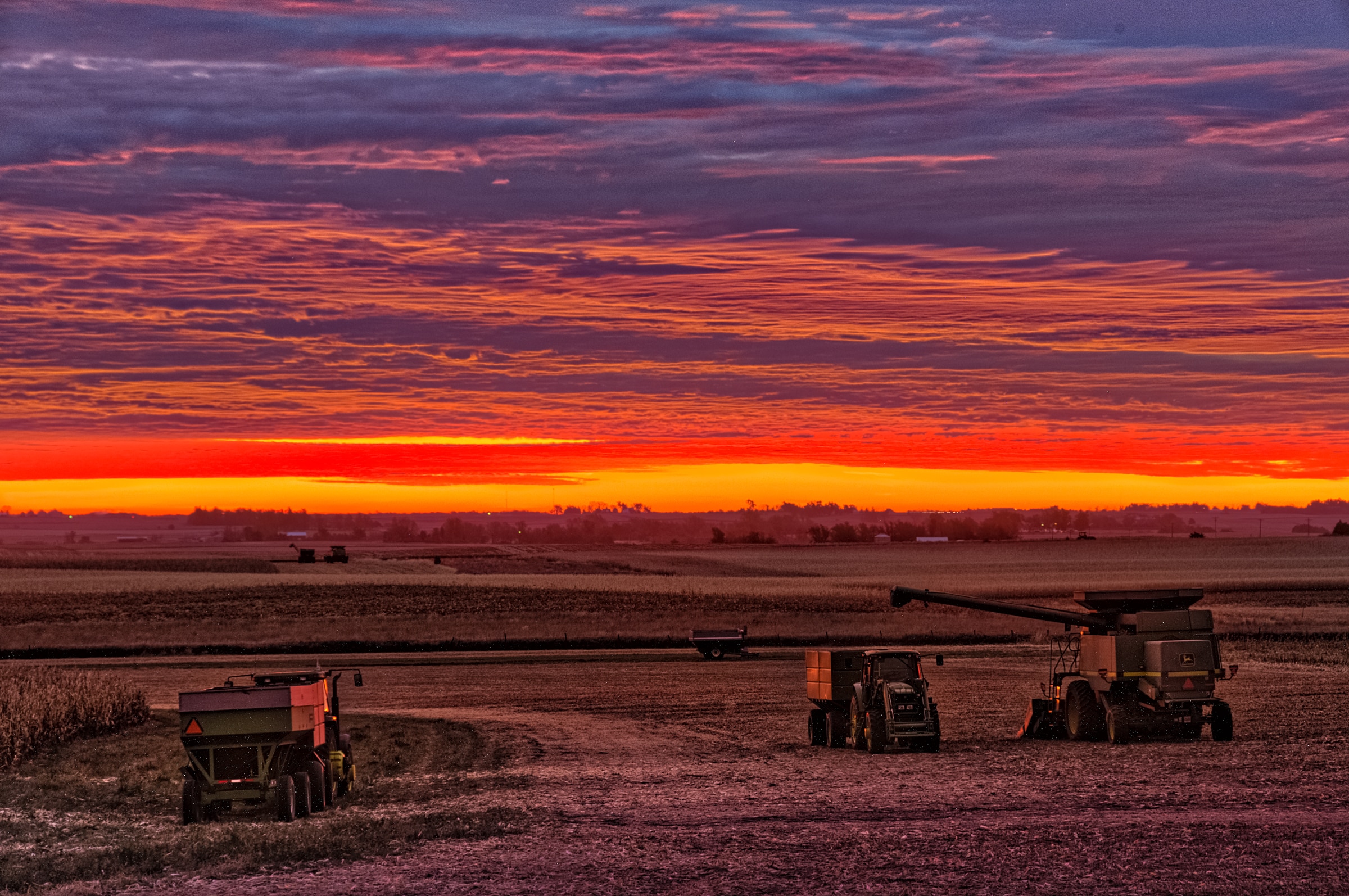 Sunrise over harvesting equipment waiting in a field near Glidden, Iowa.