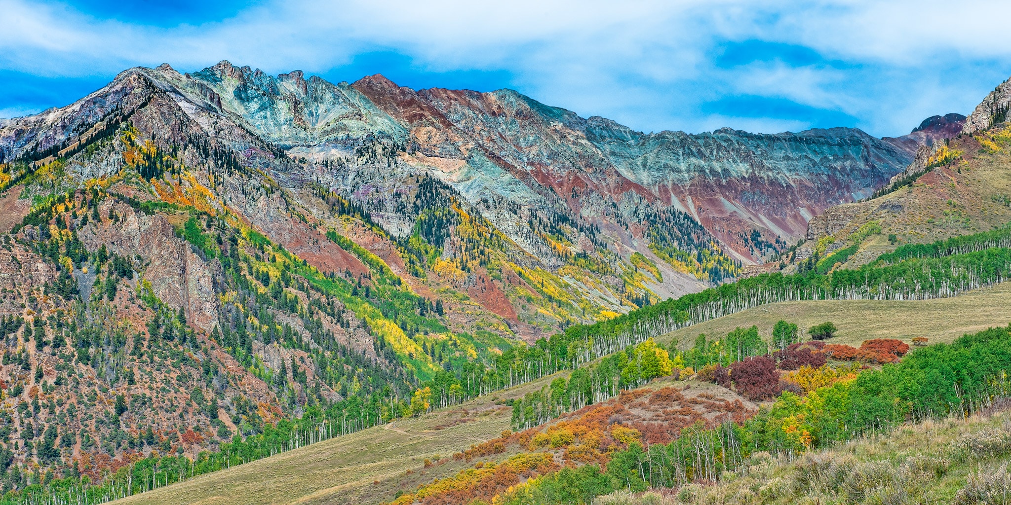 The highly mineralized rocks of the San Juan Mountains contrast with the bright fall colors of the Gambel oaks and aspen trees.