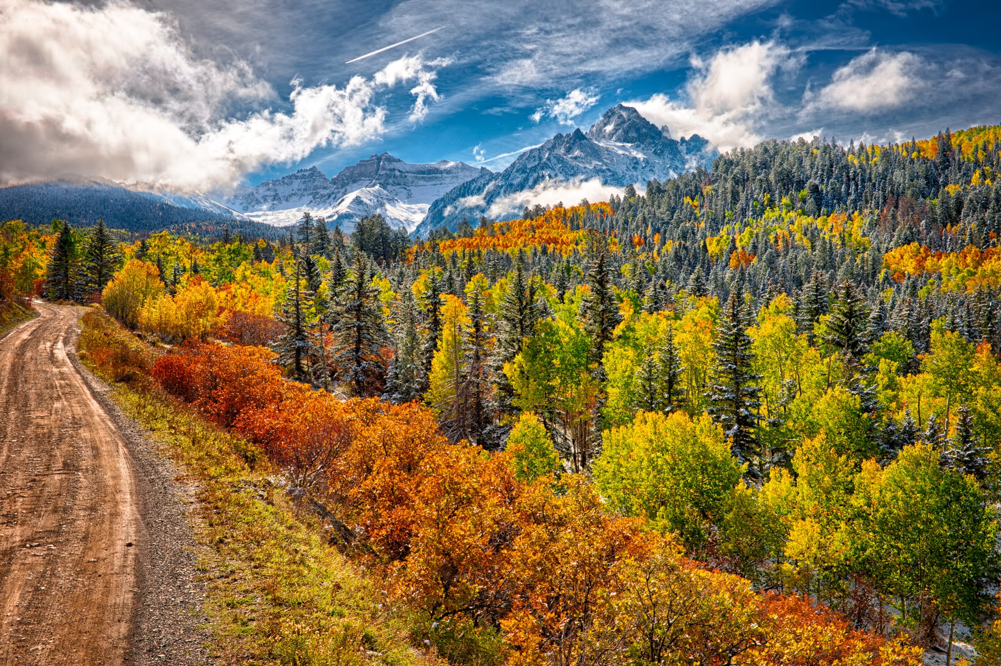 Colorful aspens and Gambel oaks treat the eye along CR 7 near Ridgway, Colorado, with the snow-capped mountains of the Sneffels Wilderness in the distance.