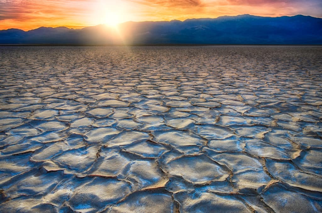 The low angle of the setting sun highlights the hexagonal plates of salt crystals in Badwater Basin in Death BValley National Park, California