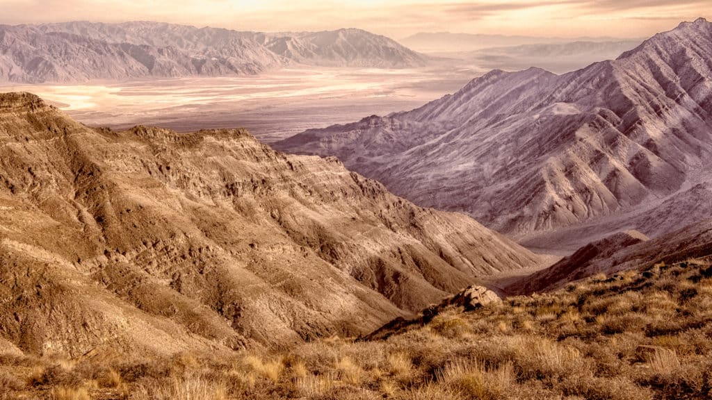 This sepia photograph shows the view from Aguereberry Point, accessible by a dirt road off Emigrant Canyon Road in Death Valley National Park, out across Death Valley and Badwater Basin to the Black Mountains to the south