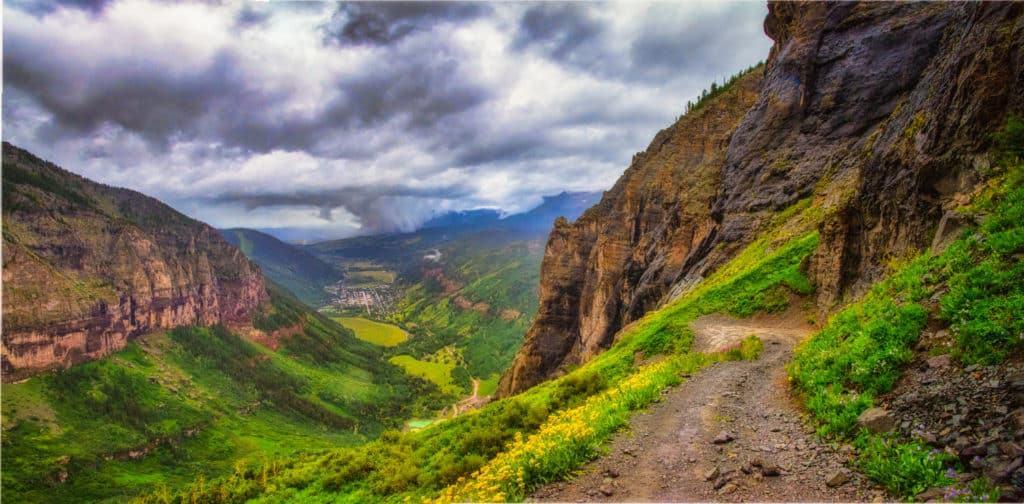 From a switchback on Black Bear Road, the town of Telluride, Colorado, becomes visible through the rain clouds and fog.
