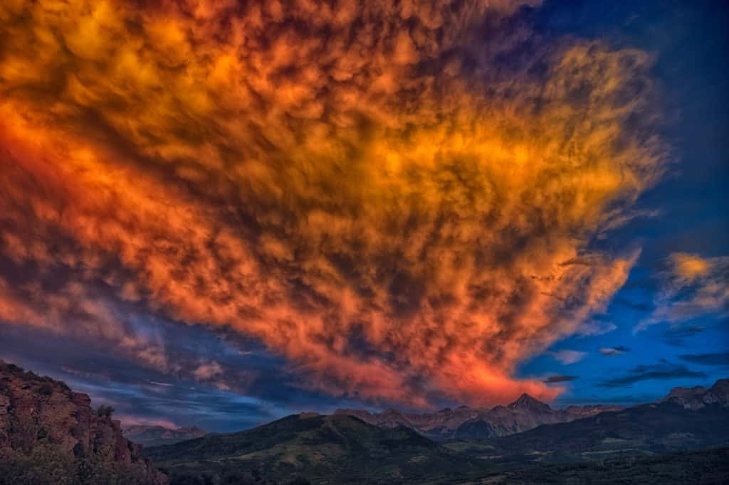 The setting sun sets fire to the clouds over the Sneffles Wilderness as seen from the Dallas Divide on Highway 62 near Ridgway, Colorado.