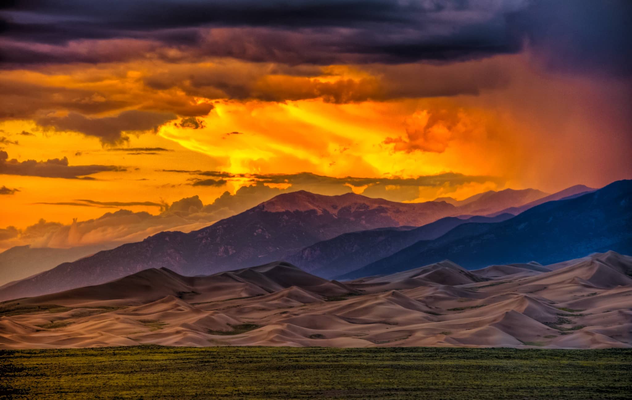 Sunsets are dramatic and colorful when competing with storm clouds at Great Sand Dunes National Park and Preserve near Alamosa, Colorado.