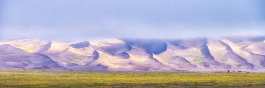 This panorama shows cloud cover shrouding the tops of the dunes on an early morning in September at Great Sand Dunes National Park and Preserve near Alamosa, Colorado.