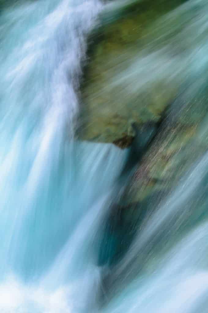 Splashing water over smoothed river rocks at McDonald Falls in Glacier National Park along Going to the Sun Road