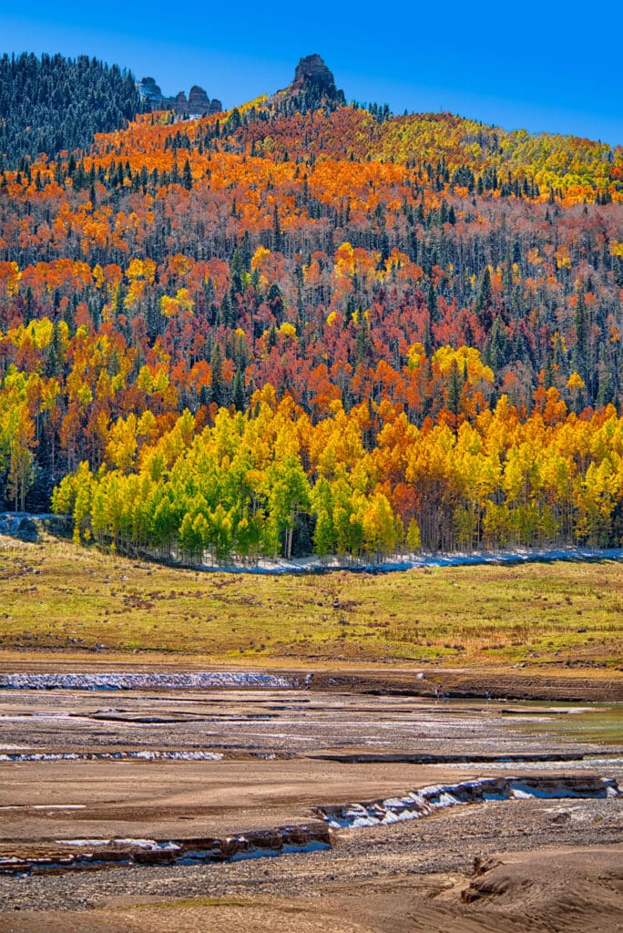 Green, yellow, orange, and red aspens march up the mountainsides above Silver Jack Reservoir on Owl Creek Pass Road near Ridgway, Colorado.