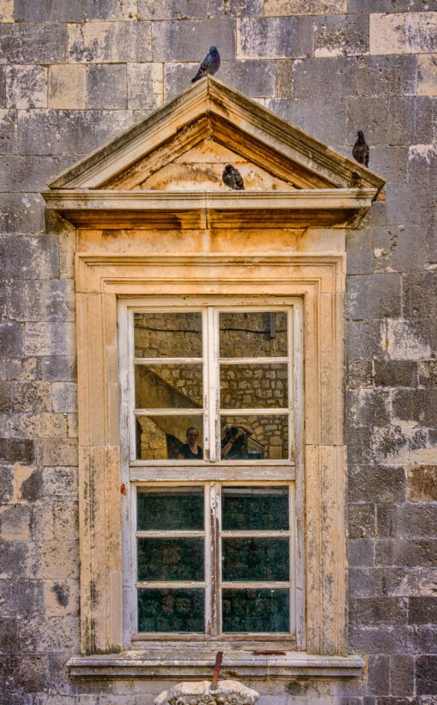 A window with a Roman-style peaked pediment as seen from the wall surrounding Dubrovnik Old City in Croatia.