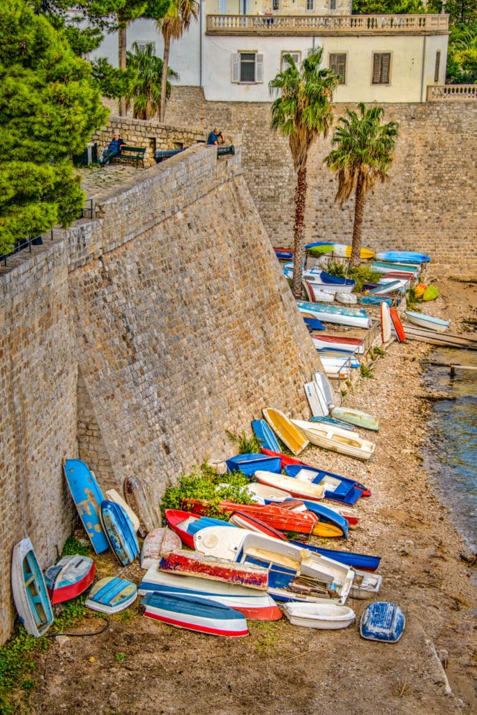 Colorful rowboats pulled onto shore against the Old Dubrovnik City walls in Croatia.