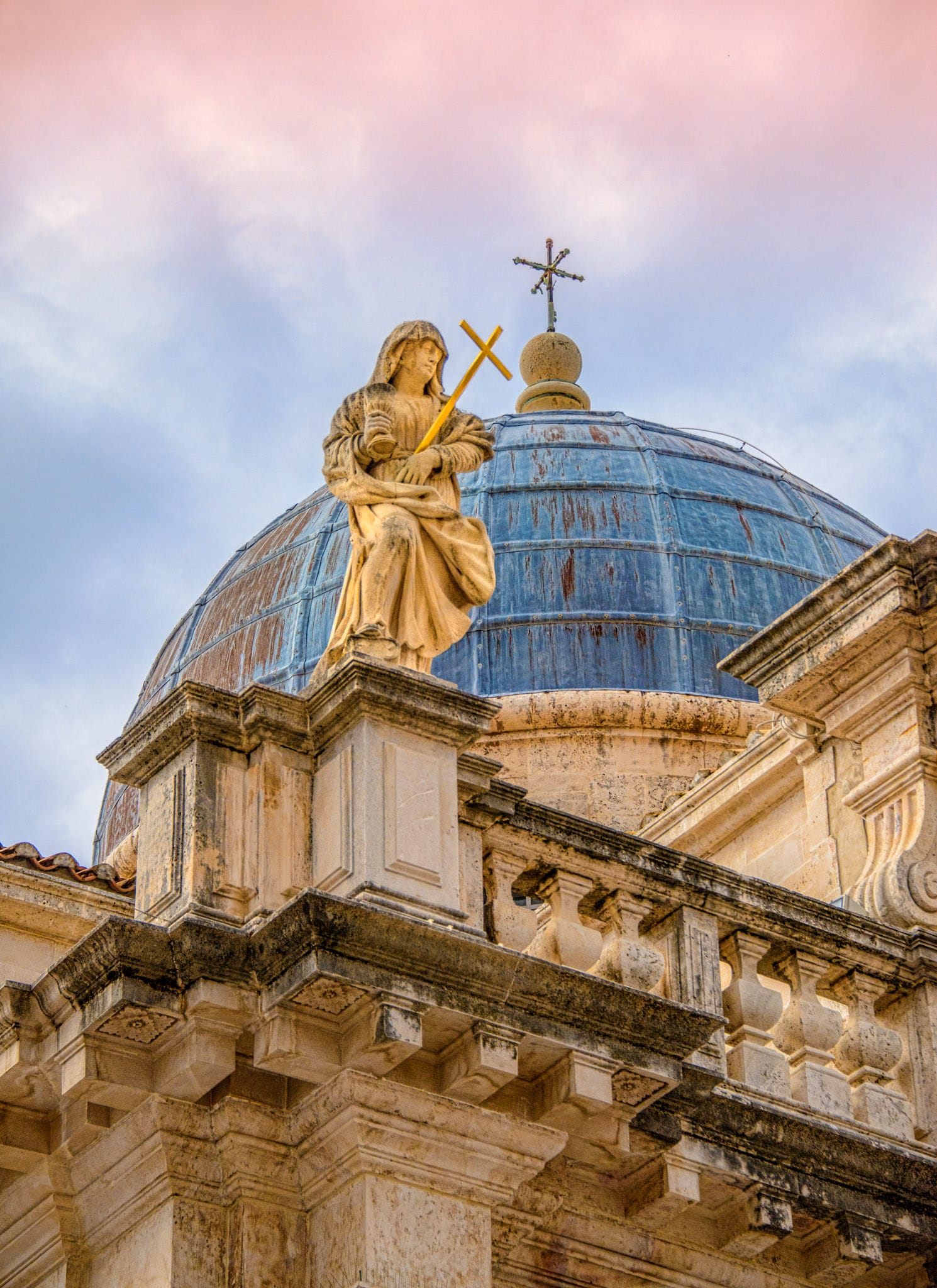 A personification of Faith sits atop a parapet on the Church of St. Blaise in Dubrovnik Old Town in Croatia.