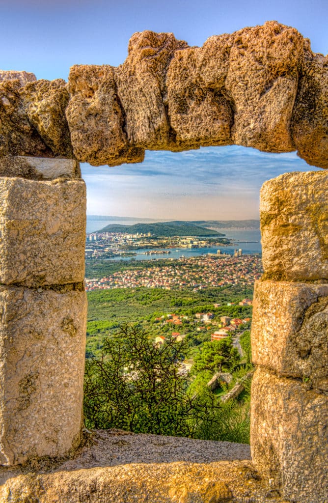 The Croatian city of Split is framed through an opening in the fortification walls of Klis Fortress.