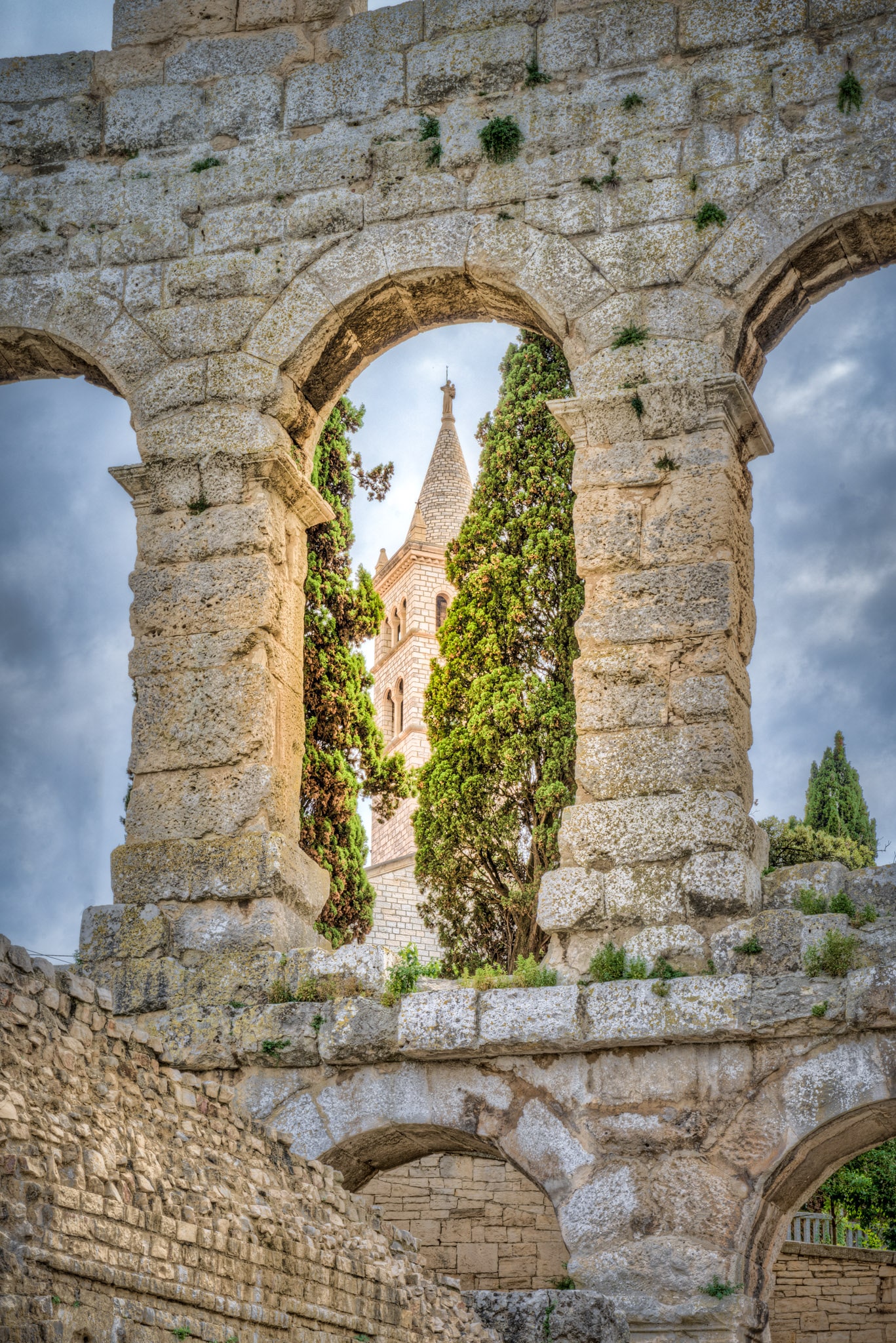 A view of the bell tower of the Church of St. Antun as seen through an upper arch in the wall of the Roman amphitheater in the Istrian city of Pula, Croatia.