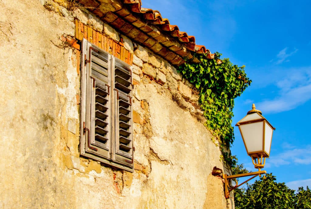 A street light and ivey adorn the ruined walls of a structure in Krk, Croatia.