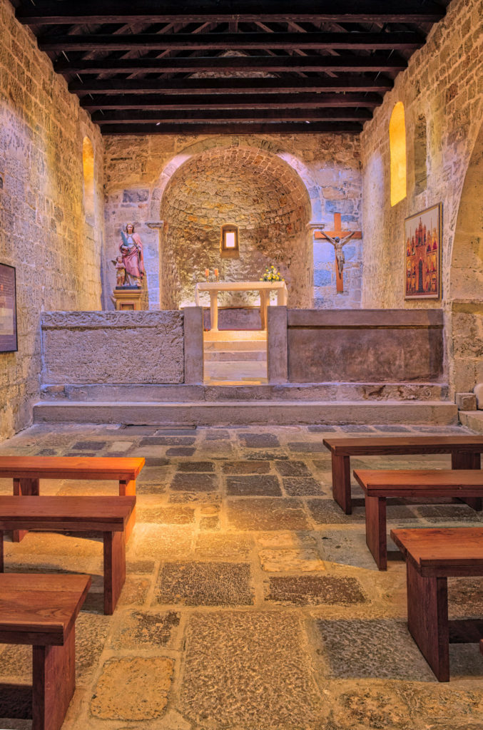 The interior of the Church of St. Lucy with a reproduction of the Baska Tablet set into the low wall separating the chancel from the nave.