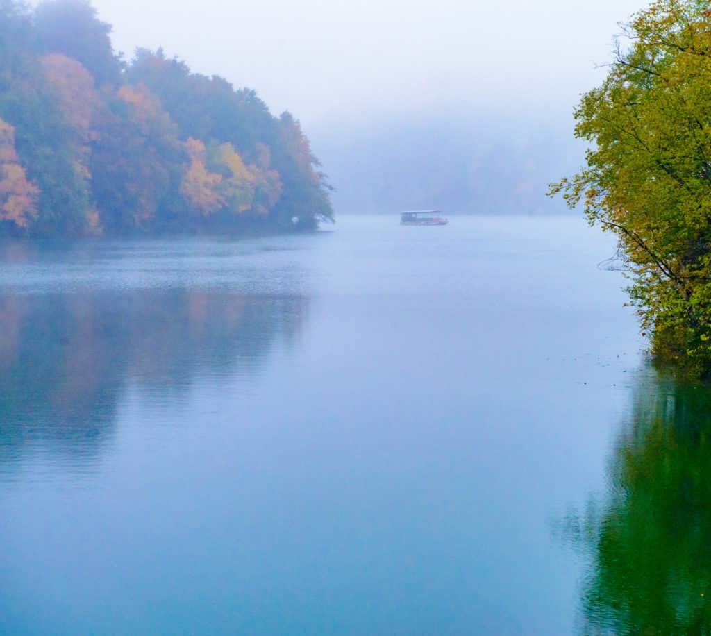 An electric ferry boat carries tourists through the fog on Lake Kozjak in Plitvice Lakes National Park in Croatia.