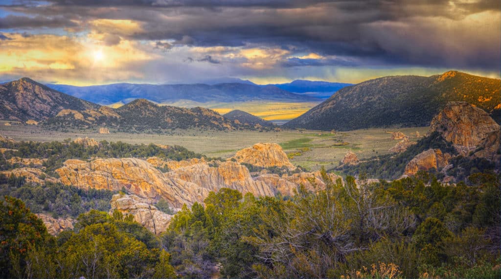 The sun shows through retreating snow clouds in City of Rocks National Reserve at sunset, near Almo, Idaho.
