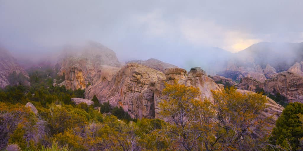 The sun peaks through retreating snow clouds in City of Rocks National Reserve at sunset, near Almo, Idaho.