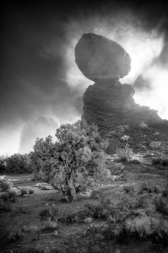 Balanced Rock wrapped in fog at morning in Arches National Park in black and white.