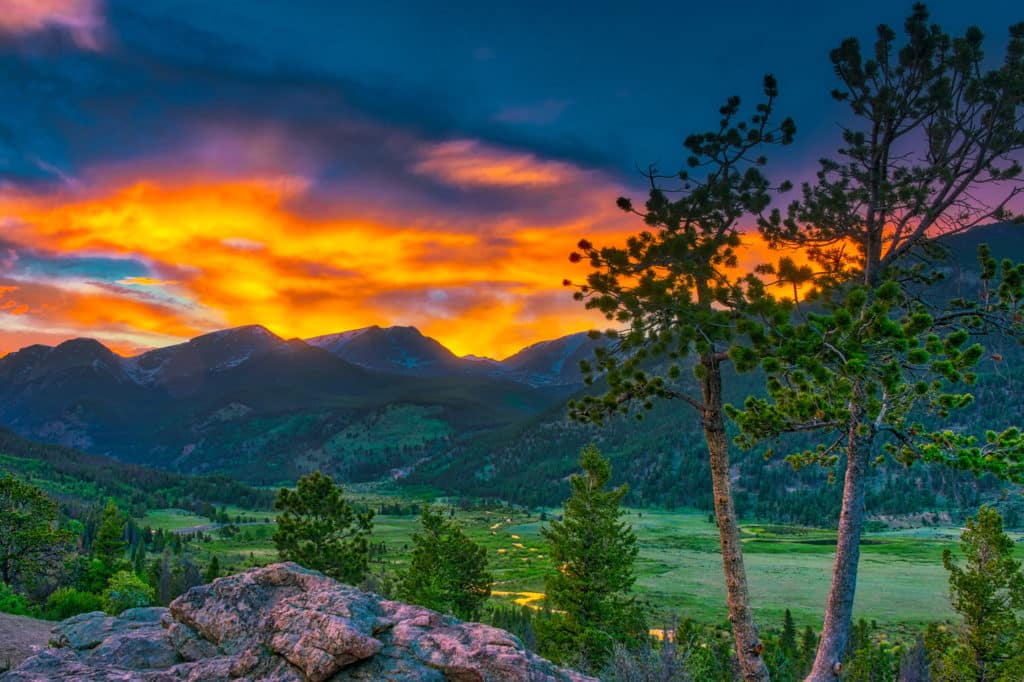 A meandering stream reflects the orange sunset from an overlook in Rocky Mountain National Park, Colorado.