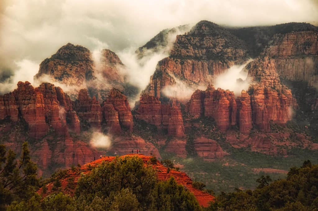 Looking east from Airport Road in Sedona, Arizona, to see fog draped over the red rocks. This is one of Sedona's vortices, so there are a number of people visible on the rock.