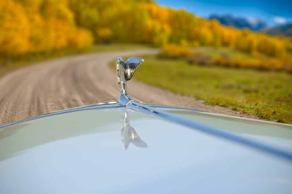 1959 Bentley S1 hood ornament from the driver's perspective on a dirt road in autumn.
