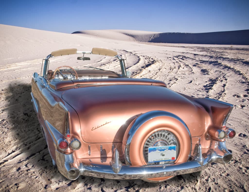 Cadillac convertible in White Sands National Monument, New Mexico, rear view showing continental kit.