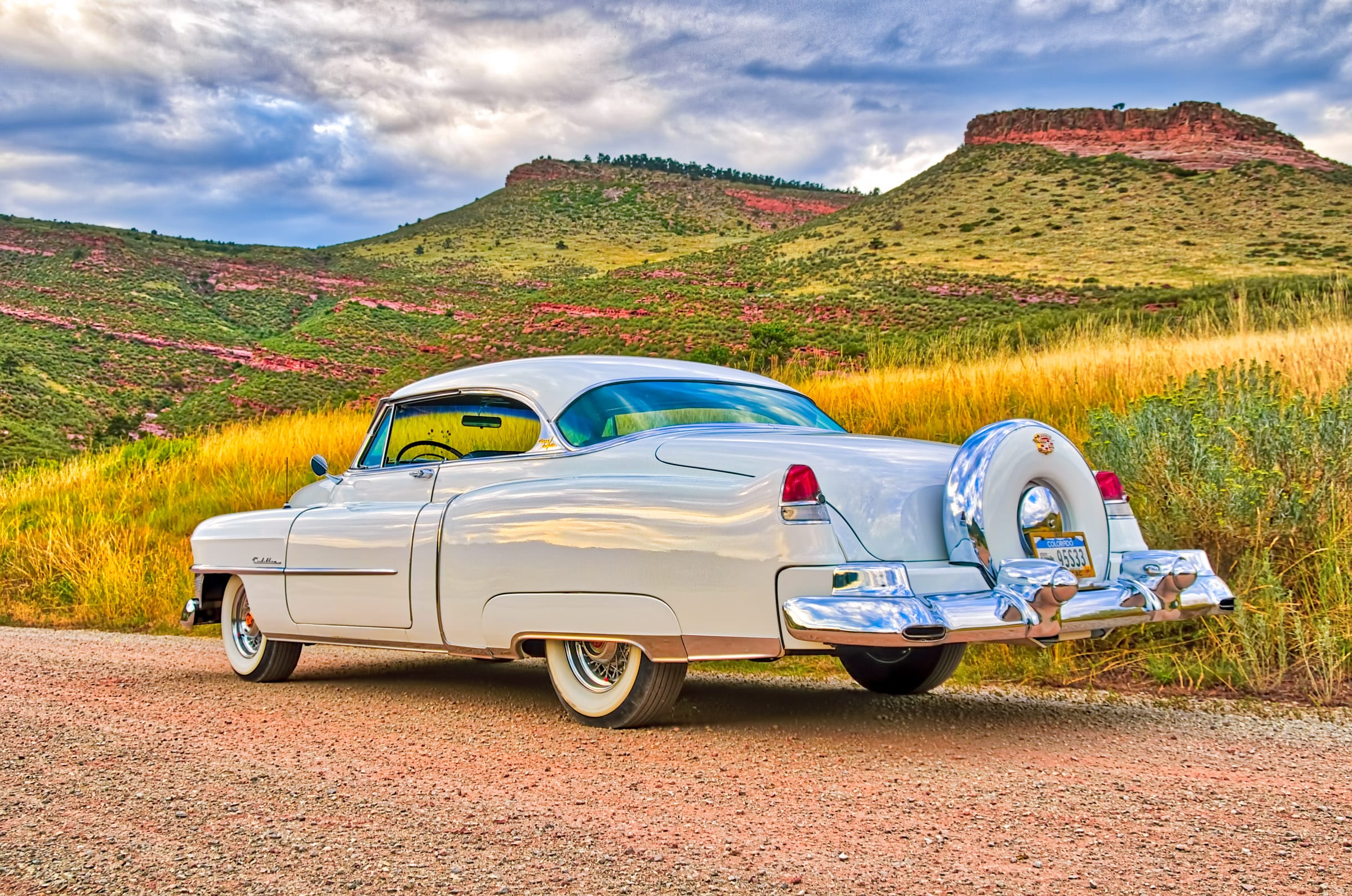1953 Cadillac Coupe deVille -Left rear three-quarter view with red buttes and clouds.