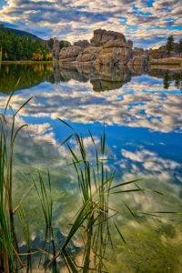 Afternoon clouds are reflected in the still waters of Sylvan Lake in Custer State Park near Custer, South Dakota.