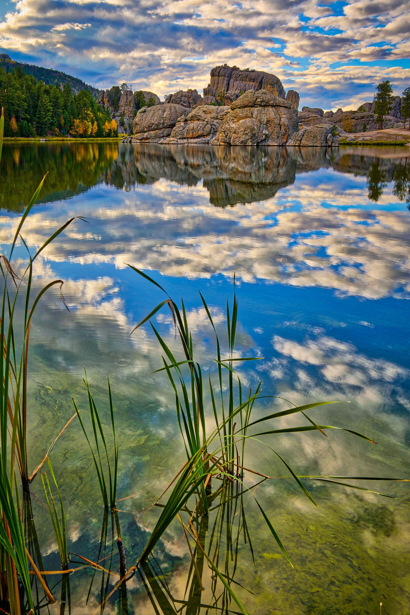Afternoon clouds are reflected in the still waters of Sylvan Lake in Custer State Park near Custer, South Dakota.