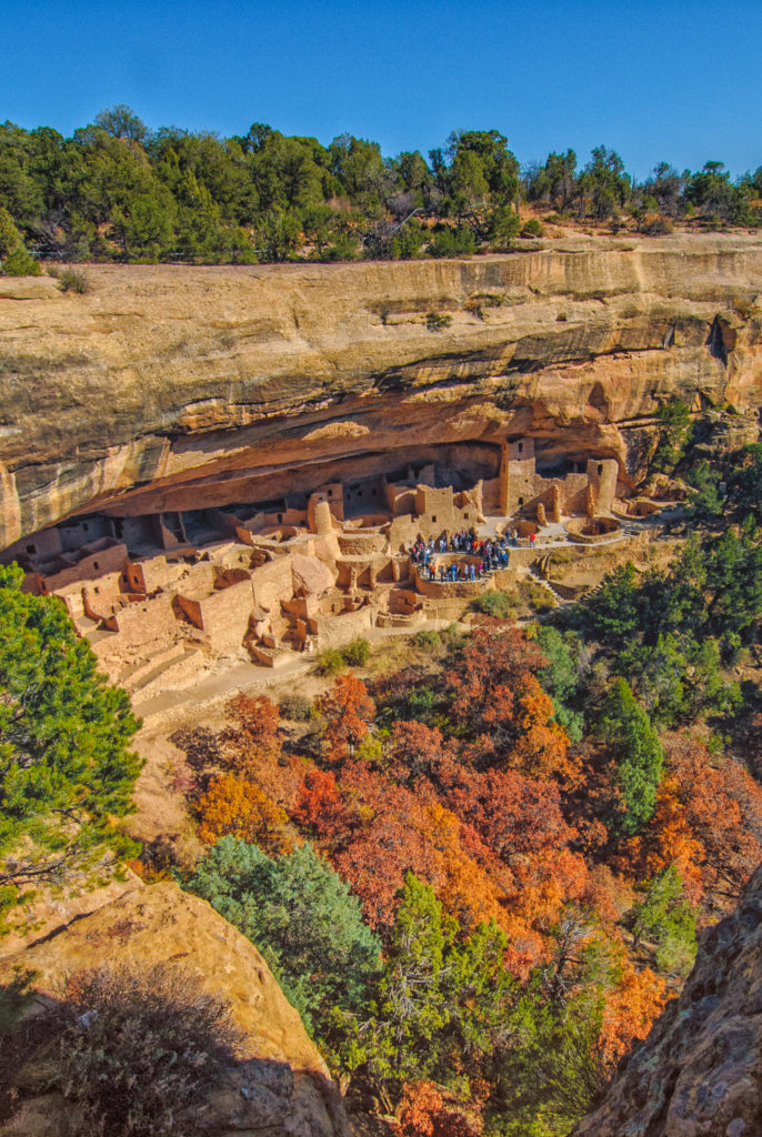 Overview of Cliff Palace in Mesa Verde National Park. Tourists encircle an open kiva.