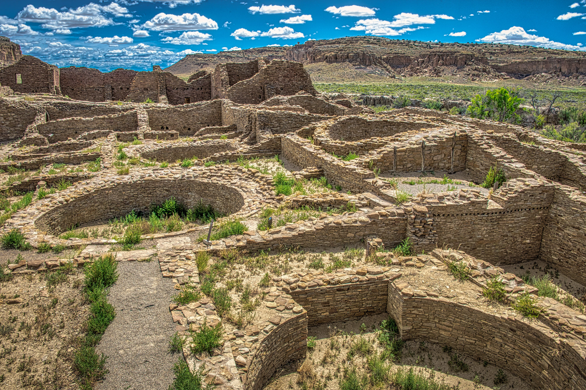 This interior view of Pueblo del Arroyo, in Chaco Canyon, New Mexico, shows several kivas, a multi-storied greathouse, and remnants of vigas.