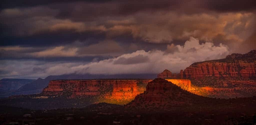 Beam of early-morning sunshine lights one butte while silhouetting another. North of Sedona, Arizona.