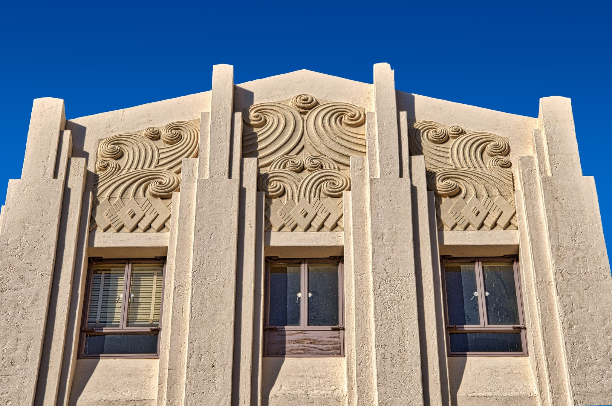 This is a close-up view of the front elevation parapet of the Cochise County Courthouse in Bisbee, Arizona. The embedded Art Deco decorations look to be carved blocks fitted into the building. They may, however, be cast concrete blocks rather than carved stone.