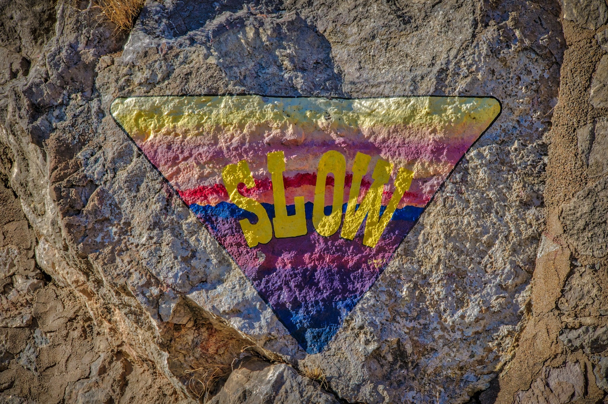 This rainbow-hued SLOW sign is painted on a stone traffic island next to Tombstone Canyon Road in Bisbee, Arizona.