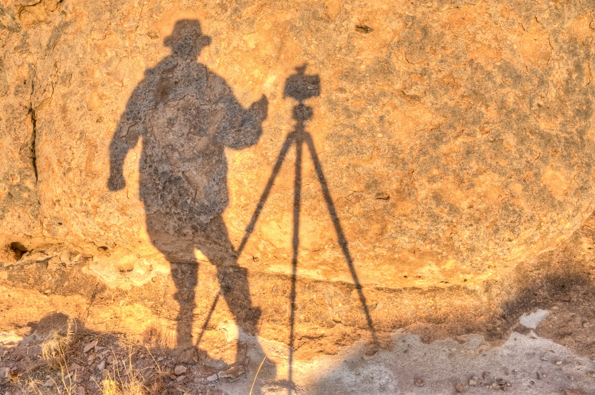 Sunrise shadow of the photographer, camera, and tripod on rock in City of Rocks State Park in New Mexico.
