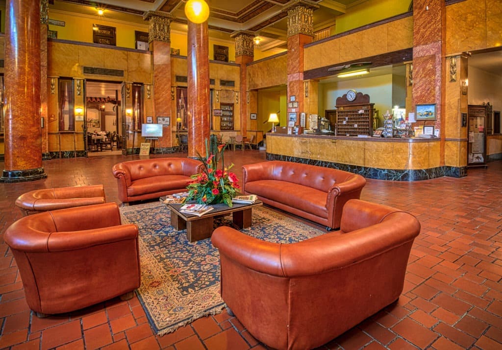 A view of the grand Hotel Gadsden lobby highlighting the leather furniture, tile floors, Italian marble, stained glass, and expansive grand staircase.